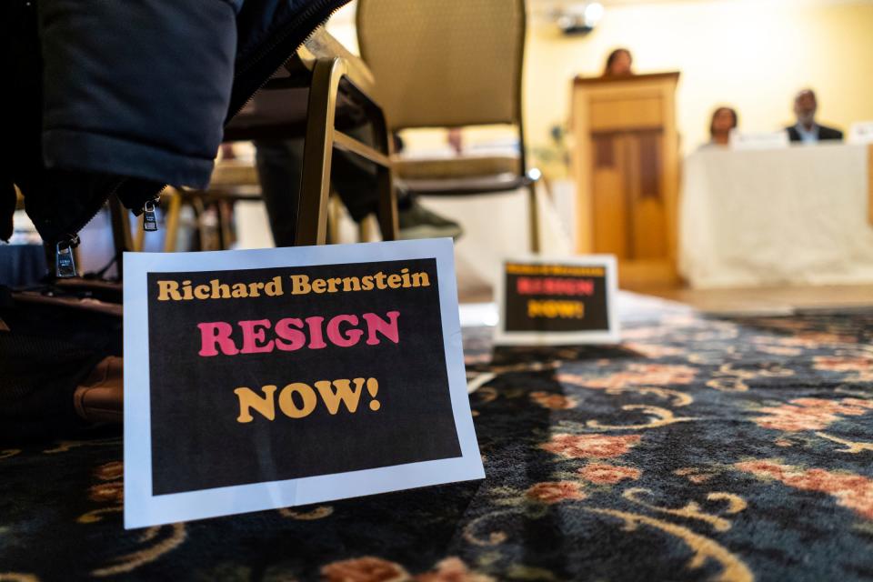 Jimmy Thomas, of Wyandotte, posted signs for Richard Bernstein to resign now as a person speaks while community organizers advocating for the formerly incarcerated called for Michigan Supreme Court Justice Bernstein to make amends with the community, condemning his comments about Justice Kyra Bolden's hiring of law clerk Peter Martel, who once served 14 years in prison for robbing a Flint-area store and shooting at police officers, during a news conference at the Tapestry Event Hall in Southfield on Jan. 12, 2023. Martel quickly resigned after Bernstein said he was "disgusted" by the hire.