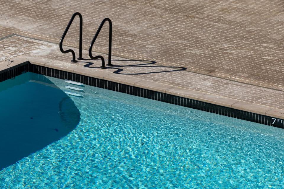 The corner of a swimming pool, with the ladder and handrails to get in or out