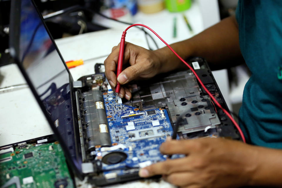 Un homme vérifie les lignes électriques sur une carte mère d'un ordinateur portable dans un centre de réparation à Colombo, Sri Lanka le 17 octobre 2017. REUTERS/Dinuka Liyanawatte