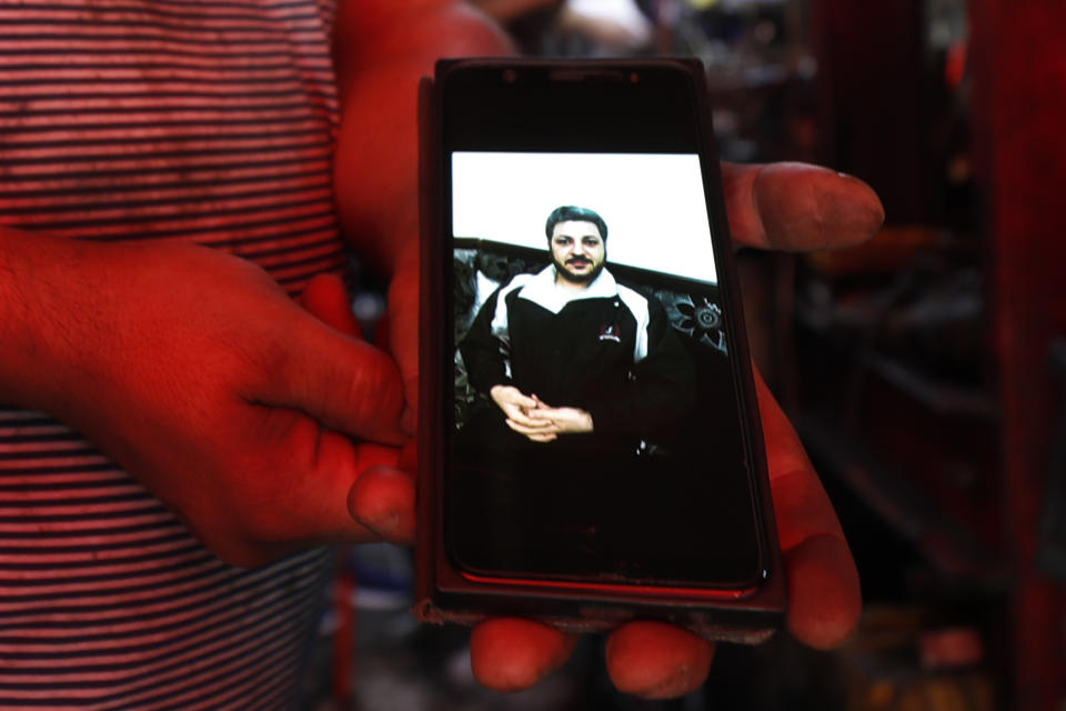 Mohammed Khier Qalaji, the brother of Firas Qalaji a Syrian man who died with his wife and his six children during the floods in the Libyan city of Derna, shows his brother picture through his mobile phone at his mechanic shop in Damascus, Syria, Saturday, Sept. 16, 2023. Firas Qalaji, 45, a car mechanic, had been living in Libya since 2000 and his wife Rana Khateeb and their six children were to be buried in Libya, the family said in a statement. (AP Photo/Omar Sanadiki)