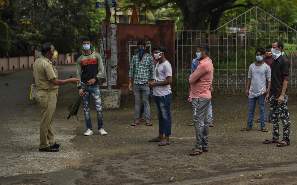 A Kerala police person briefs migrant workers from northern states looking for information on the next train available for them to return to their villages in Kochi, southern Kerala state, India, Sunday, May 17, 2020. The government has started a limited number of trains to facilitate the travel, of thousands of migrant laborers who have been returning to their villages after losing jobs because of a countrywide lockdown imposed in late March to contain the spread of the coronavirus. (AP Photo/R S Iyer)