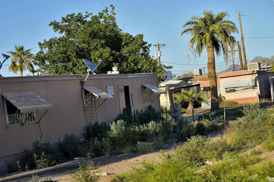 Home are overrun with weeds at the Periwinkle Mobile Home Park, Thursday, April 11, 2023, in Phoenix. Residents of the park are facing an eviction deadline of May 28 due to a private university's plan to redevelop the land for student housing. (AP Photo/Matt York)