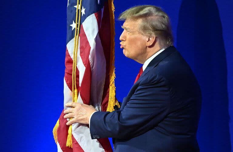 El ex presidente de Estados Unidos y aspirante a la presidencia de 2024, Donald Trump, besa la bandera de Estados Unidos cuando llega para hablar durante la reunión anual de la Conferencia de Acción Política Conservadora (CPAC) 
