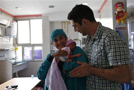 Briton Rekha Patel, 42, holds her week-old-baby girl Gabriella, as her husband Daniele Fabbricatore, 39, watches inside an intensive care unit at the Akanksha IVF centre in Anand town, about 70 km (44 miles) south from the western Indian city of Ahmedabad August 25, 2013. REUTERS/Mansi Thapliyal