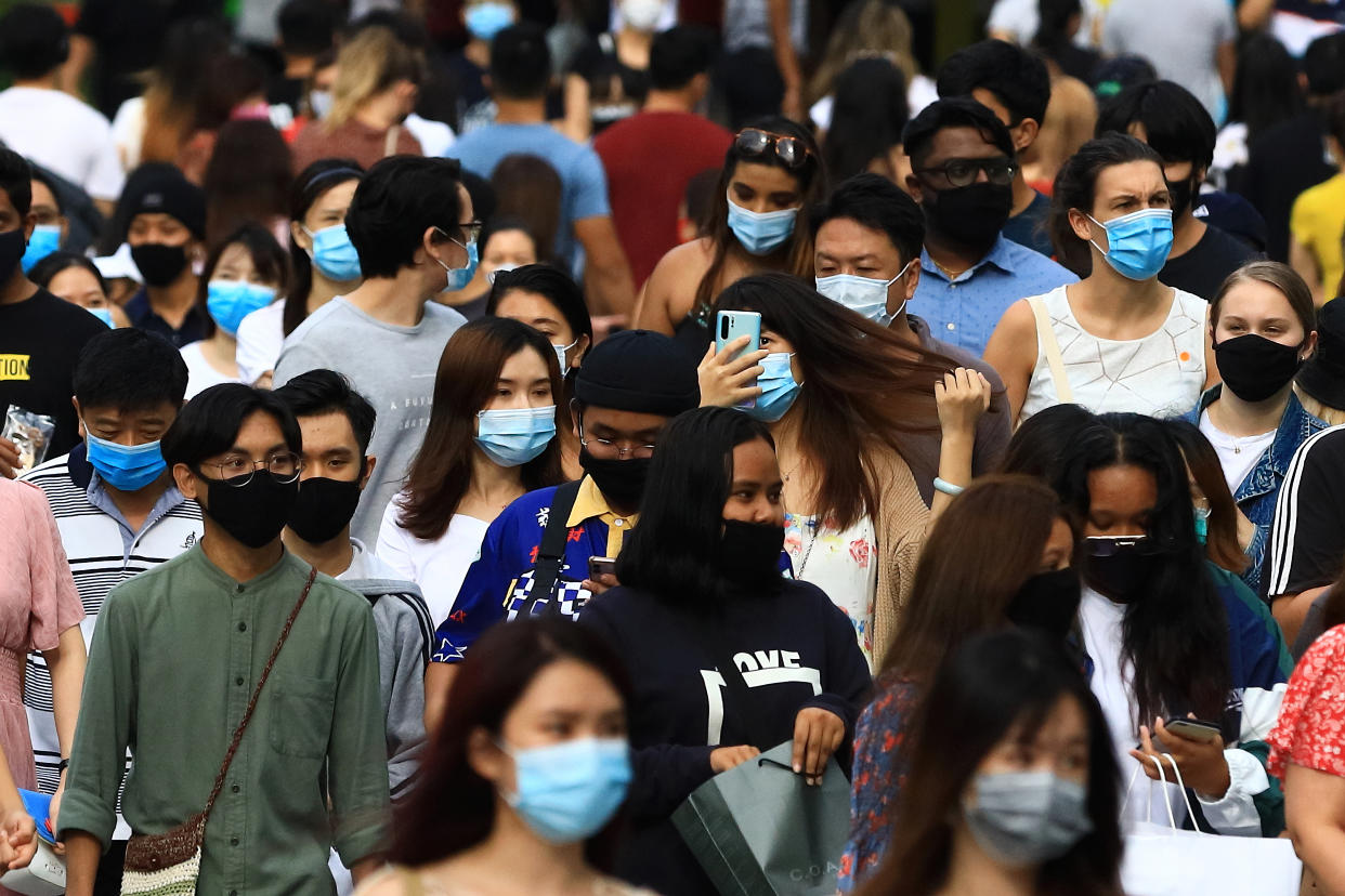 SINGAPORE - JUNE 20:  People wearing protective masks walk along Orchard Road shopping belt on June 20, 2020 in Singapore. From June 19, Singapore started to further ease the coronavirus (COVID-19) restrictions by allowing social gatherings up to five people, re-opening of retail outlets and dining in at food and beverage outlets, subjected to safe distancing. Parks, beaches, sports amenities and public facilities in the housing estates will also reopen. However, large scale events, religious congregations, libraries, galleries and theatres will remain closed.  (Photo by Suhaimi Abdullah/Getty Images)