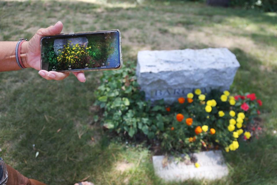 Marci Radin points out a difference in flower beds from her visit a year ago, inferring that someone locally is coming to visit the gravestone other than herself.