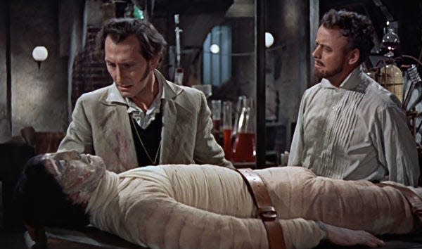 Christopher Lee as the monster lies on a gurney inspected by Dr. Frankenstein (Peter Cushing, left) and his assistant (Robert Urquhart) in "The Curse of Frankenstein" (1957). Warner Home Video (courtesy)