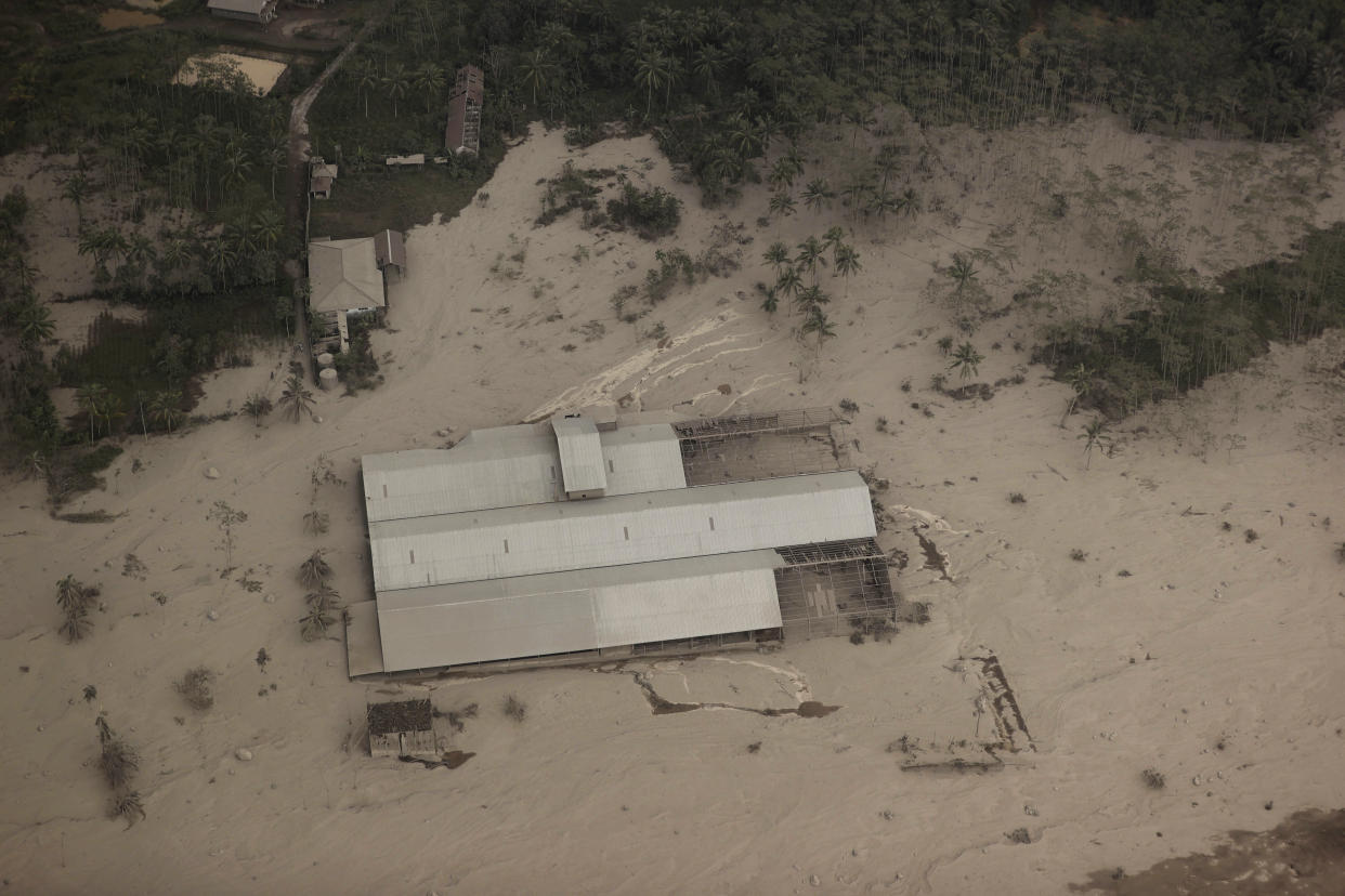 A factory building is covered by ash from the eruption of Mount Semeru in Lumajang district, East Java province, Indonesia, Sunday, Dec. 5, 2021. The death toll from eruption of the highest volcano on Indonesia's most densely populated island of Java has risen with scores still missing, officials said Sunday as rain continued to pound the region and hamper the search.(AP Photo/Trisnadi)