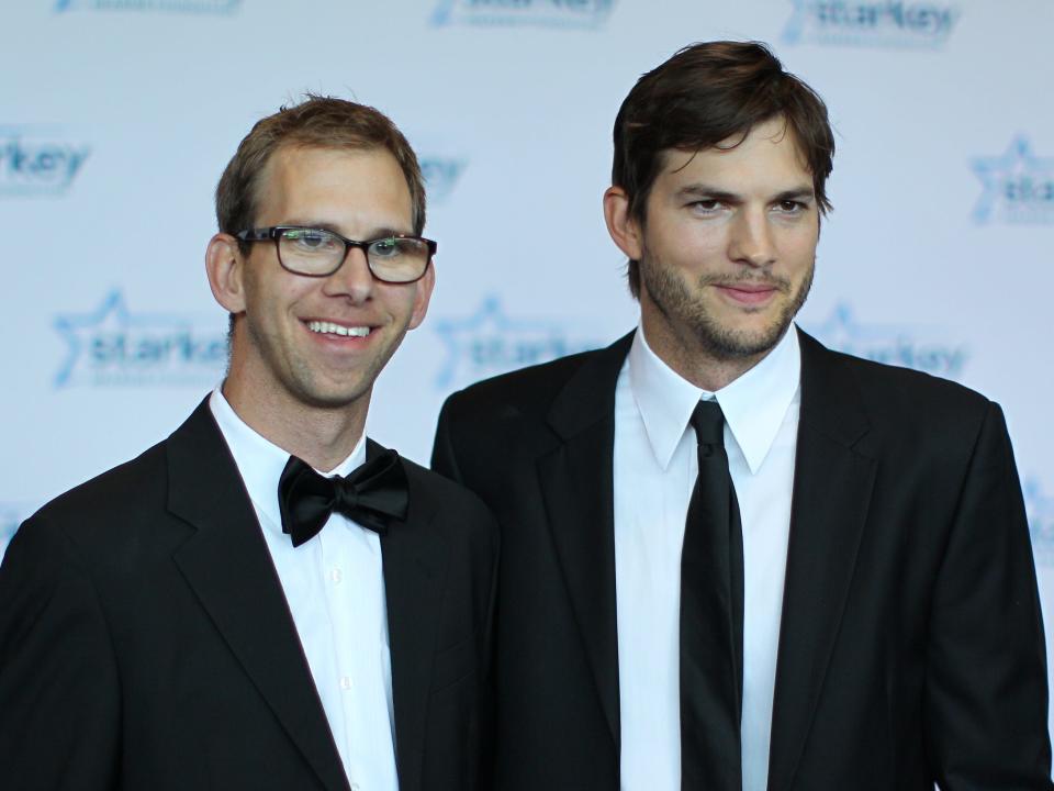 Ashton Kutcher and Michael Kutcher stand at a red carpet event.