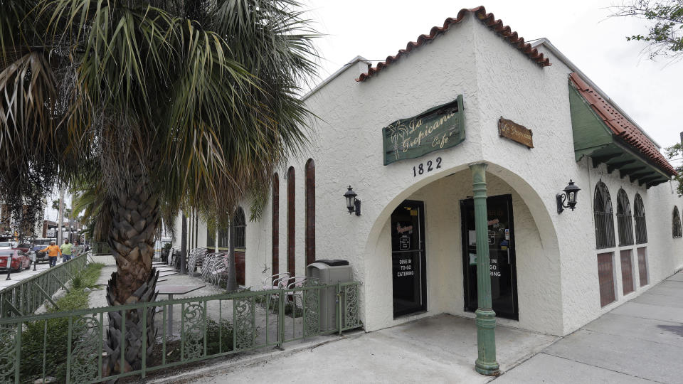 FILE- In this June 3, 2020 file photo, workmen walk by the shuttered La Tropicana Cafe in Tampa, Fla. The cafe, which first acted as a hub for immigrants when it opened in 1963 and has since been a stop for politicians campaigning in the area, has joined the long list of businesses lost to the coronavirus pandemic. (AP Photo/Chris O'Meara, FILE)