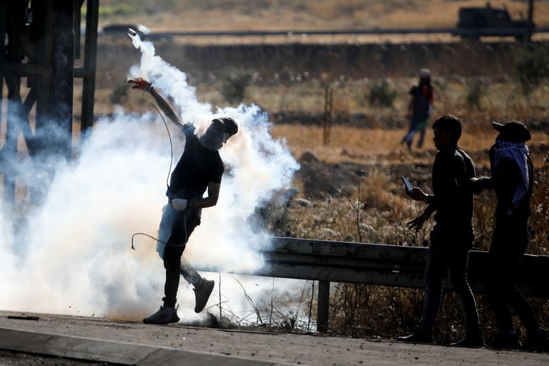 Un manifestante palestino devuelve una granada de gas lacrimógeno durante la protesta contra Israel por la violencia transfronteriza entre militantes palestinos en Gaza y el Ejército israelí, cerca del puesto de control de Hawara, cercano a Nablus, en la Cisjordania ocupada por Israel