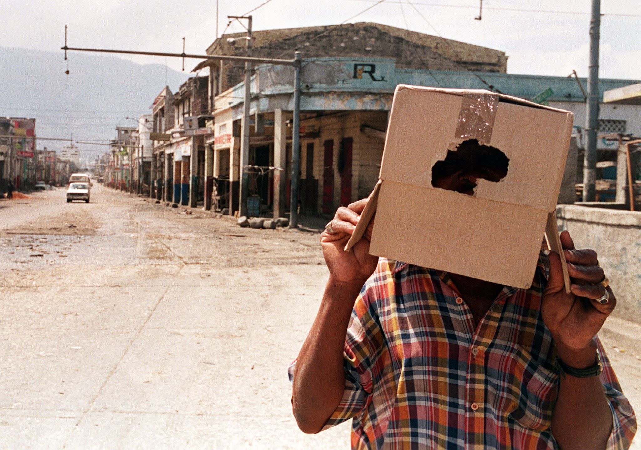 1998: A man looks at an eclipse through a cardboard box in Port-au-Prince, Haiti. 