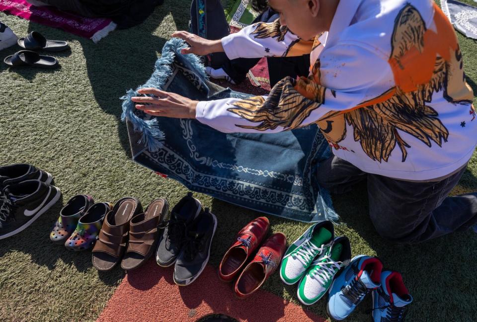 Yusef Syed lays his prayer rug down on the infield turf at the Pierce College football stadium in Los Angeles.