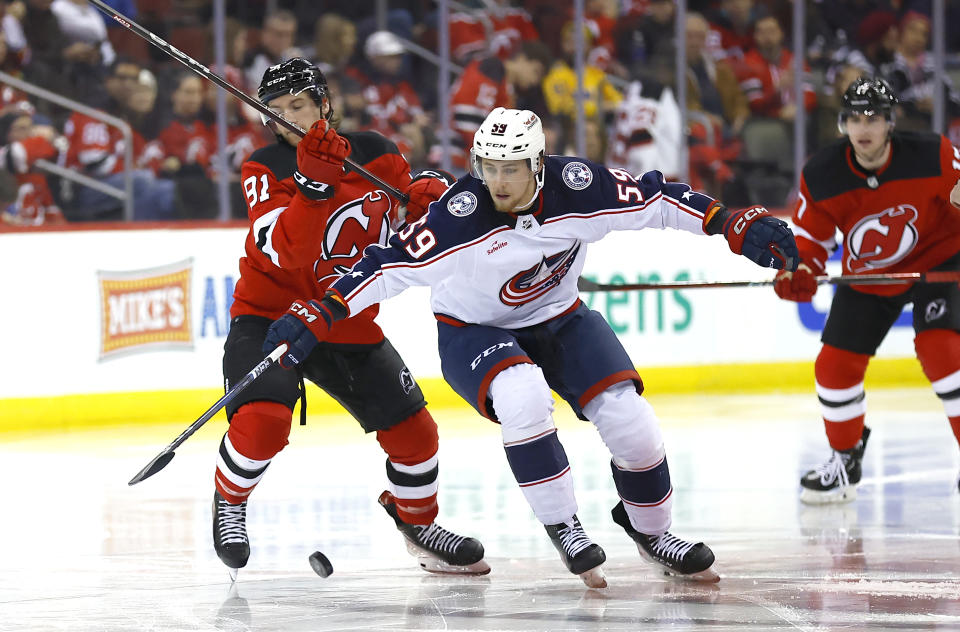 Columbus Blue Jackets right wing Yegor Chinakhov (59) battles New Jersey Devils center Dawson Mercer (91) for the puck during the second period of an NHL hockey game Wednesday Dec. 27, 2023, in Newark, N.J. (AP Photo/Noah K. Murray)