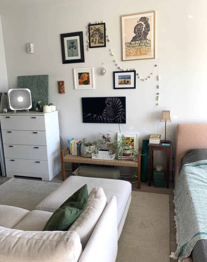 Living room area with white dresser and wall of framed art.