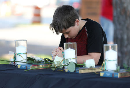 A young boy prays during a vigil held at the Texas First Bank after a shooting left several people dead at Santa Fe High School in Santa Fe, Texas, U.S., May 18, 2018. REUTERS/Trish Badger