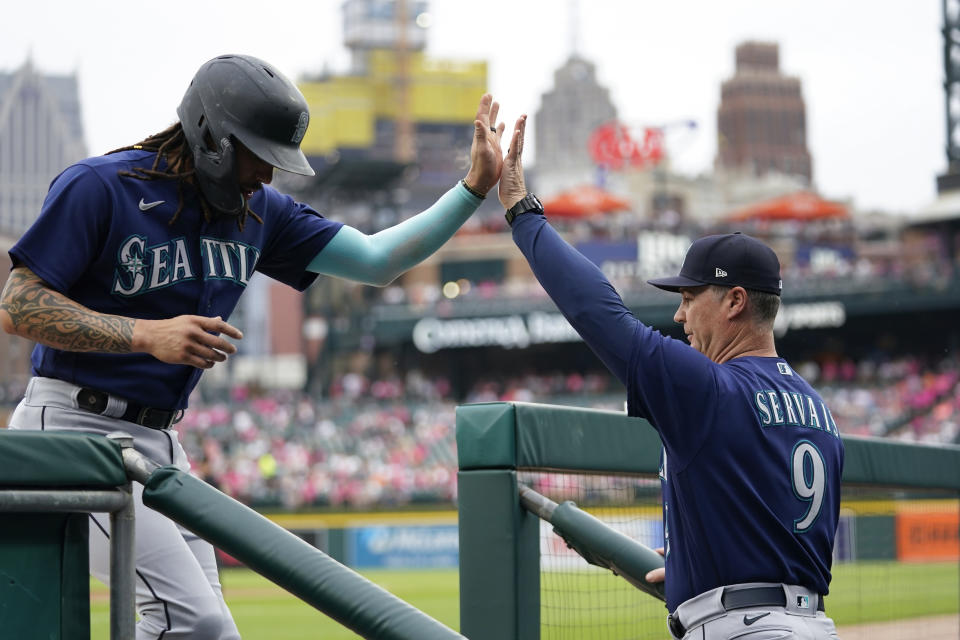 Seattle Mariners' J.P. Crawford, left, celebrates with manager Scott Servais (9) after scoring against the Detroit Tigers during the first inning of a baseball game Friday, May 12, 2023, in Detroit. (AP Photo/Paul Sancya)