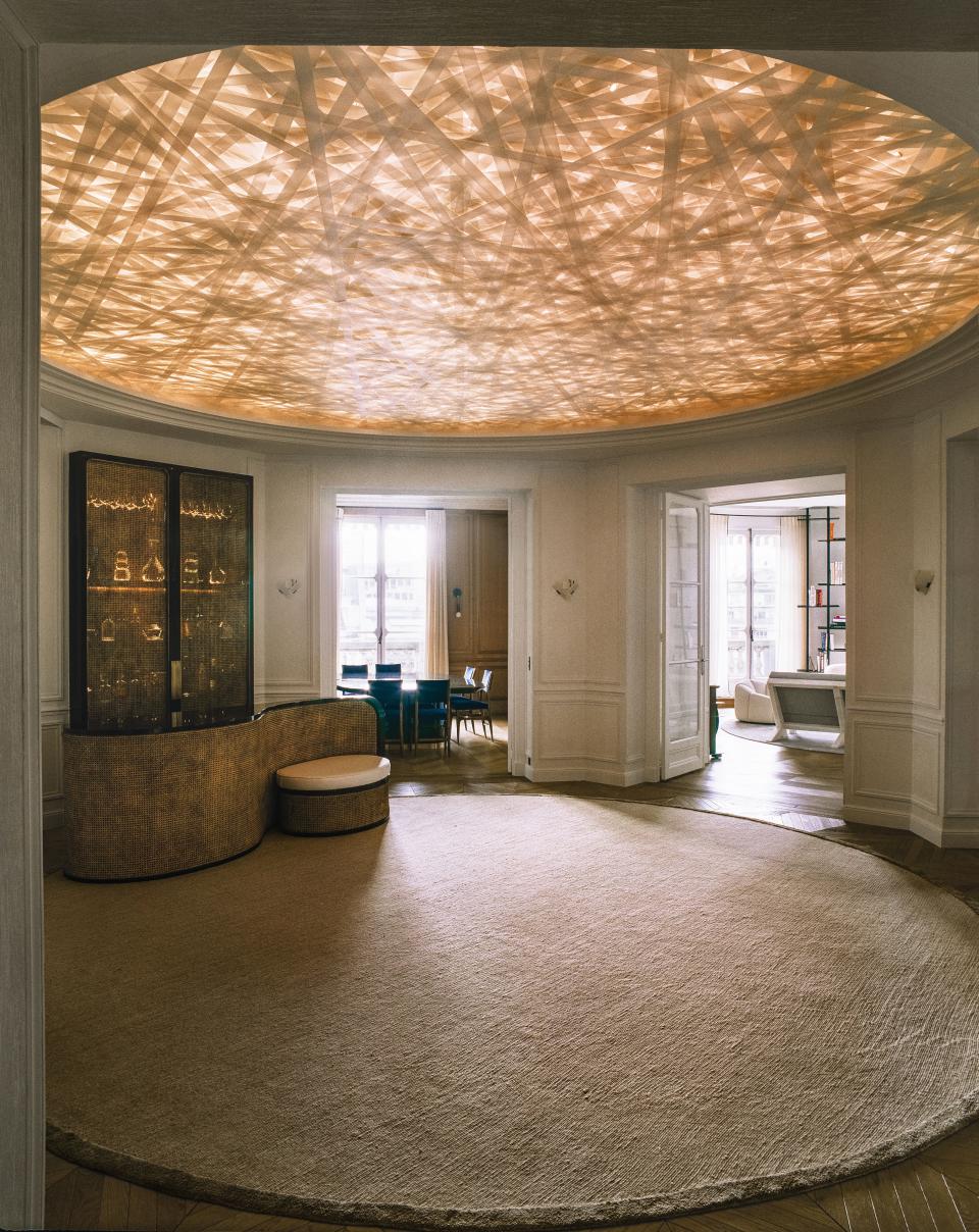 Stanislas-designed bar sits on a bespoke silk rug by J.D. Staron in the circular entrance hall. The ceiling installation was created by artist Yann Kersalé.