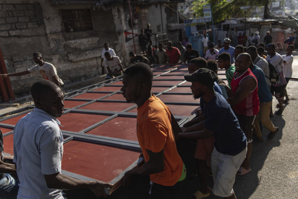 Neighbors raise a metal gate as they work to install it as a barricade as protection against gangs, in the Petion-Ville neighborhood of Port-au-Prince, Haiti, Saturday, April 20, 2024. (AP Photo/Ramon Espinosa)