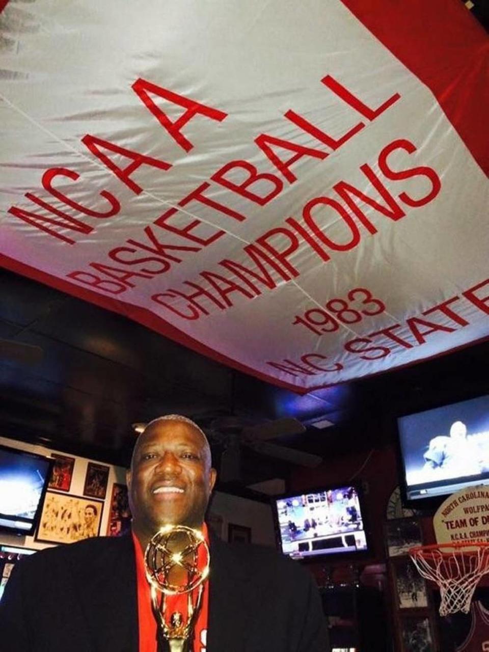 Dereck Whittenburg, of the NC State stars of 1983, stands underneath a championship banner at Amedeo’s as he displayed the Emmy won from ESPN’s 30 for 30 documentary “Survive and Advance.”