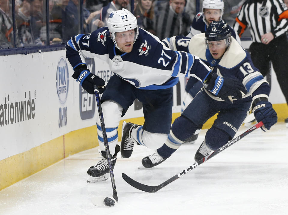Winnipeg Jets' Nikolaj Ehlers, left, of Denmark, tries to clear the puck as Columbus Blue Jackets' Cam Atkinson chases him behind the net during the second period of an NHL hockey game Wednesday, Jan. 22, 2020, in Columbus, Ohio. (AP Photo/Jay LaPrete)