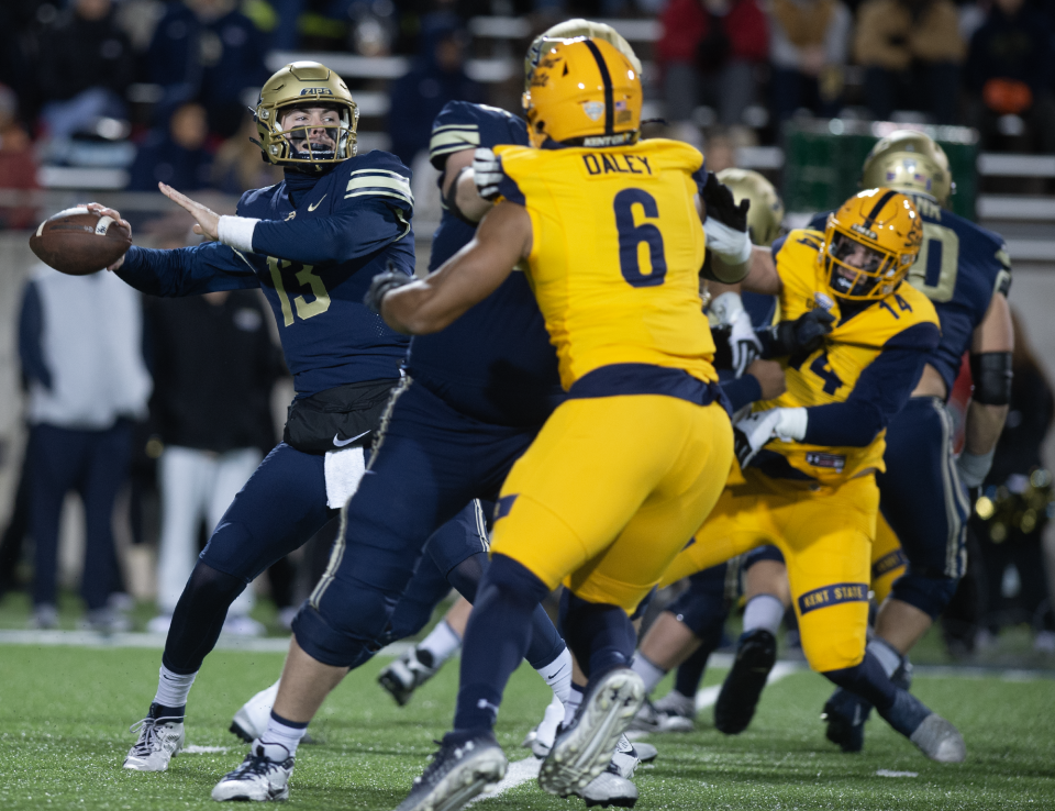 University of Akron quarterback Jeff Undercuffler Jr. throws a pass as the Kent State defense closes in Wednesday night in Akron.