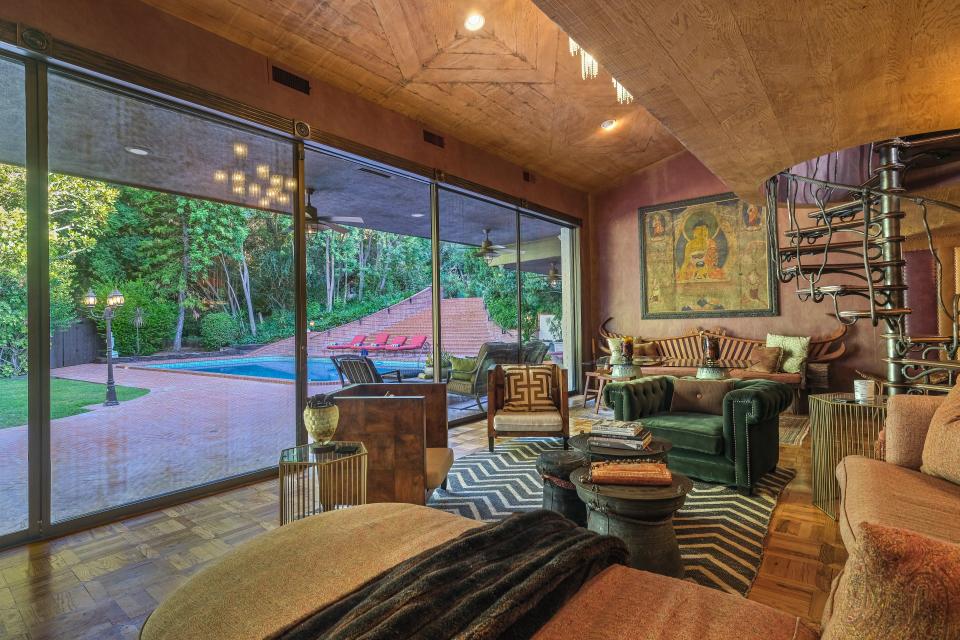 The living room looks out at the pool, which is unusually located in front of the home.