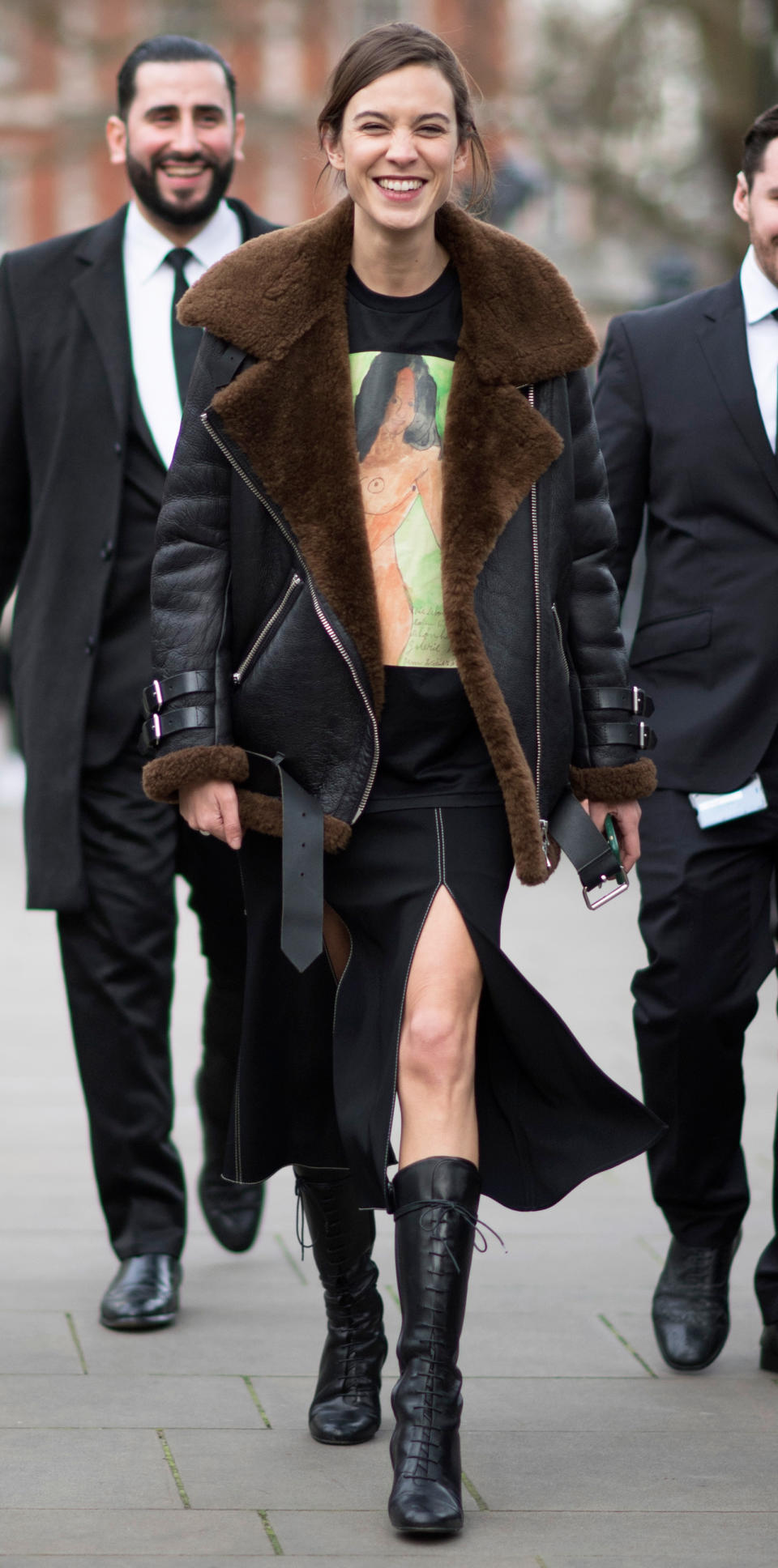 <p>Chung kept warm during London Fashion Week in a shearling-lined coat (get a similar style <a rel="nofollow noopener" href="https://click.linksynergy.com/fs-bin/click?id=93xLBvPhAeE&subid=0&offerid=390098.1&type=10&tmpid=8157&RD_PARM1=http%253A%252F%252Fshop.nordstrom.com%252Fs%252Fbetsey-johnson-mixed-media-faux-shearling-jacket%252F4345148%253Forigin%253Dcategory-personalizedsort%2526fashioncolor%253DBLACK%25252F%252520CREAM&u1=ISAlexaChungStreetStyle3.22JA" target="_blank" data-ylk="slk:here;elm:context_link;itc:0;sec:content-canvas" class="link ">here</a>), black graphic tee, and lace-up boots, but still showed a little leg with a black, thigh-high slit skirt. </p>