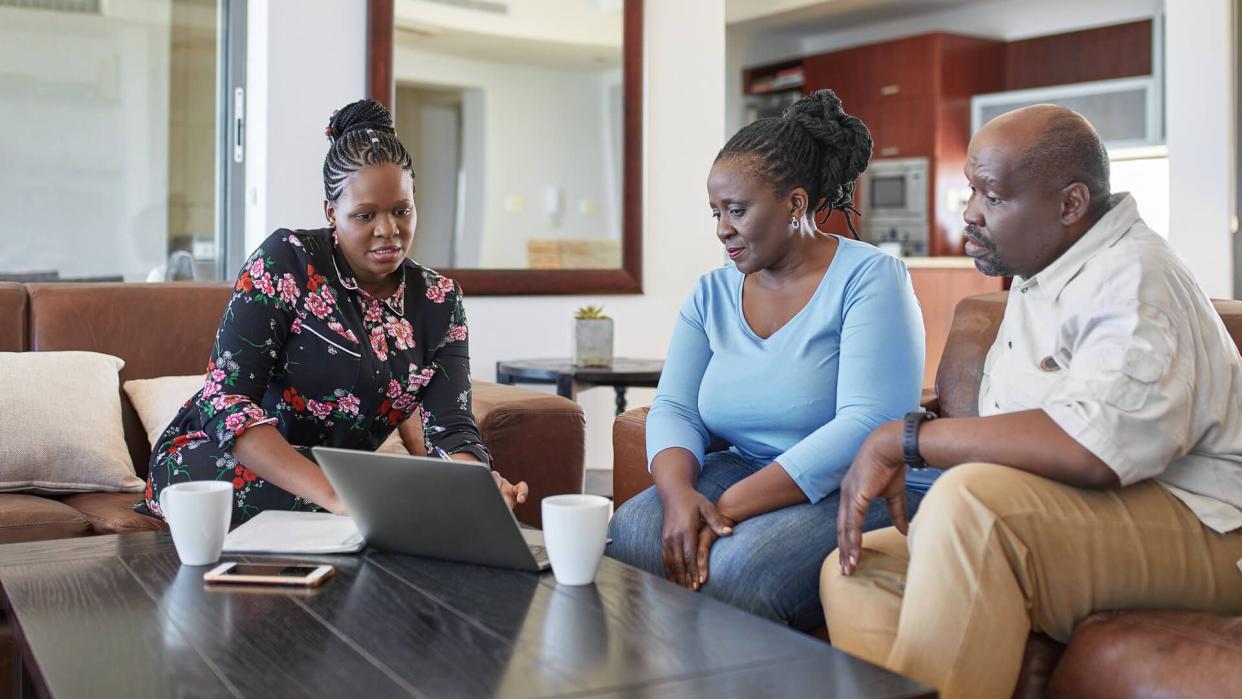 Relaxed African mature Couple at home with financial advisor.