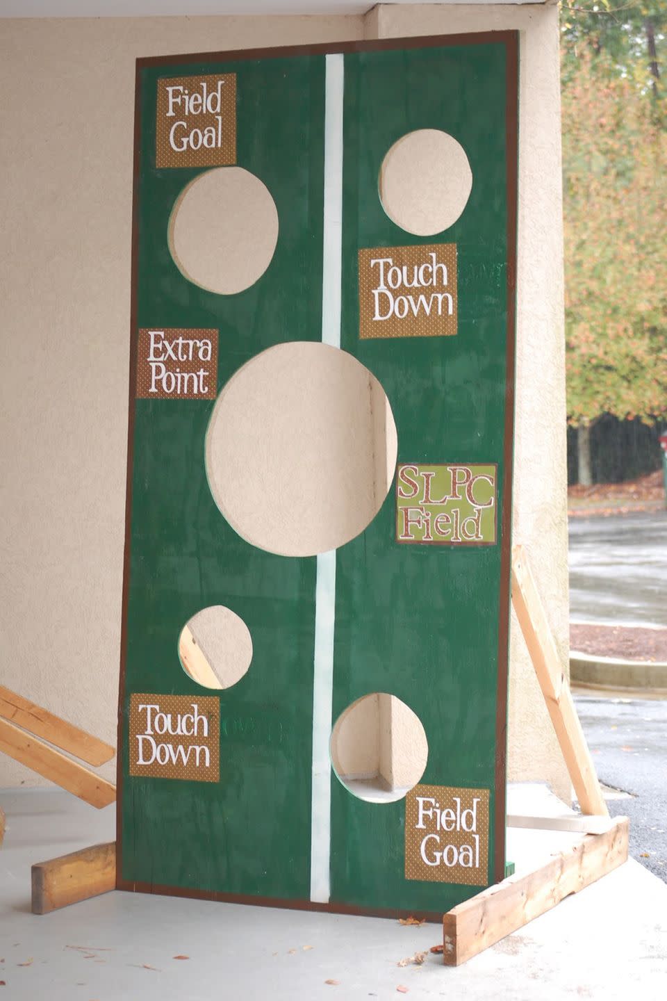 upright wooden football toss game with several various sized holes