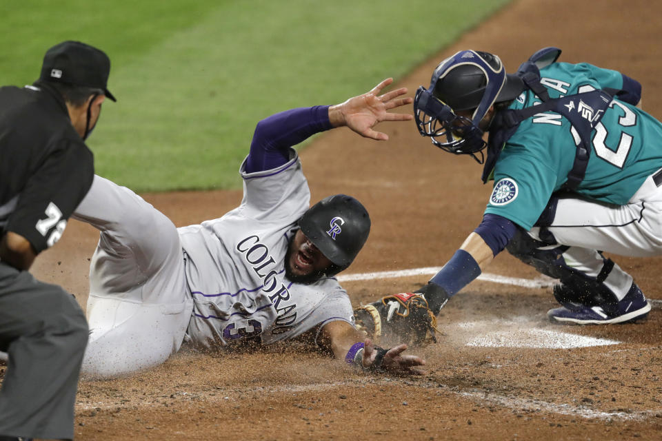 Colorado Rockies' Elias Diaz slides safely across home as Seattle Mariners catcher Austin Nola puts on a late tag in the third inning of a baseball game Friday, Aug. 7, 2020, in Seattle. (AP Photo/Elaine Thompson)