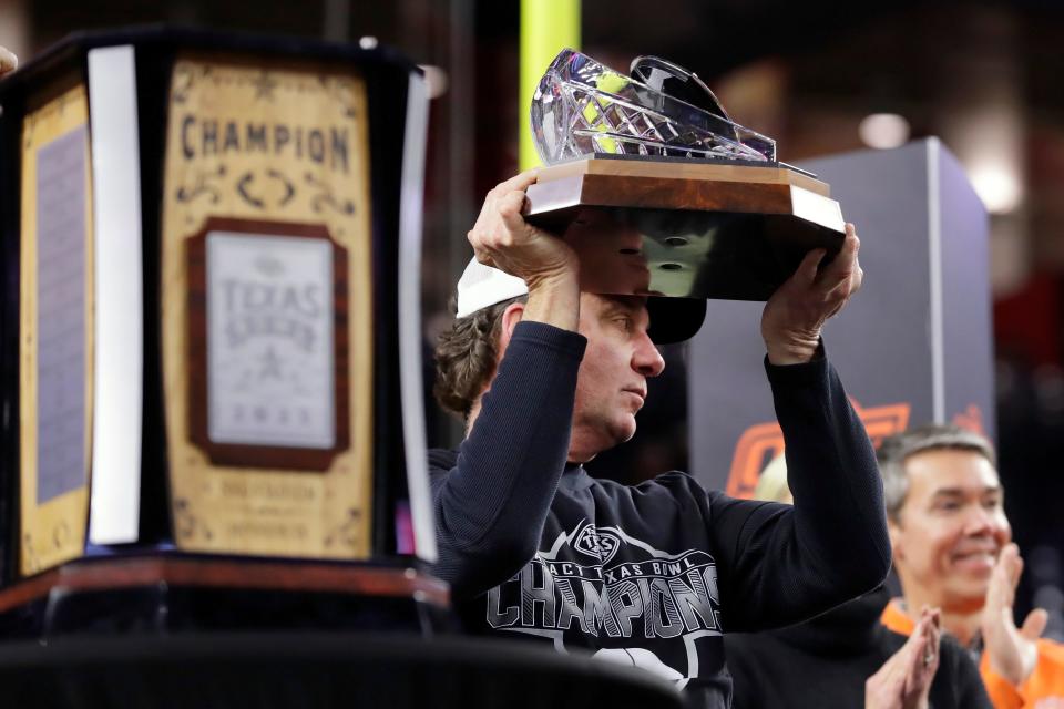 Oklahoma State coach Mike Gundy hoists the Robert C. McNair Trophy after the team's win over Texas A&M in the Texas Bowl NCAA football game Wednesday, Dec. 27, 2023, in Houston. (AP Photo/Michael Wyke)