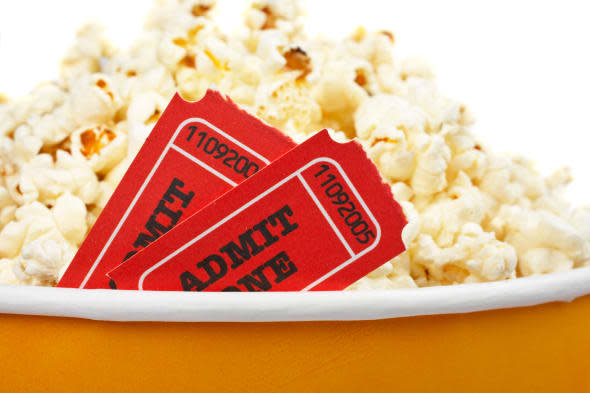 Detail of popcorn in a bucket and two tickets over a white background. Tickets on focus and shallow DOF