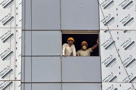 Labourers look out from a window of a data centre building under construction at the Gujarat International Finance Tec-City (GIFT) at Gandhinagar, in the western Indian state of Gujarat, April 10, 2015. REUTERS/Amit Dave