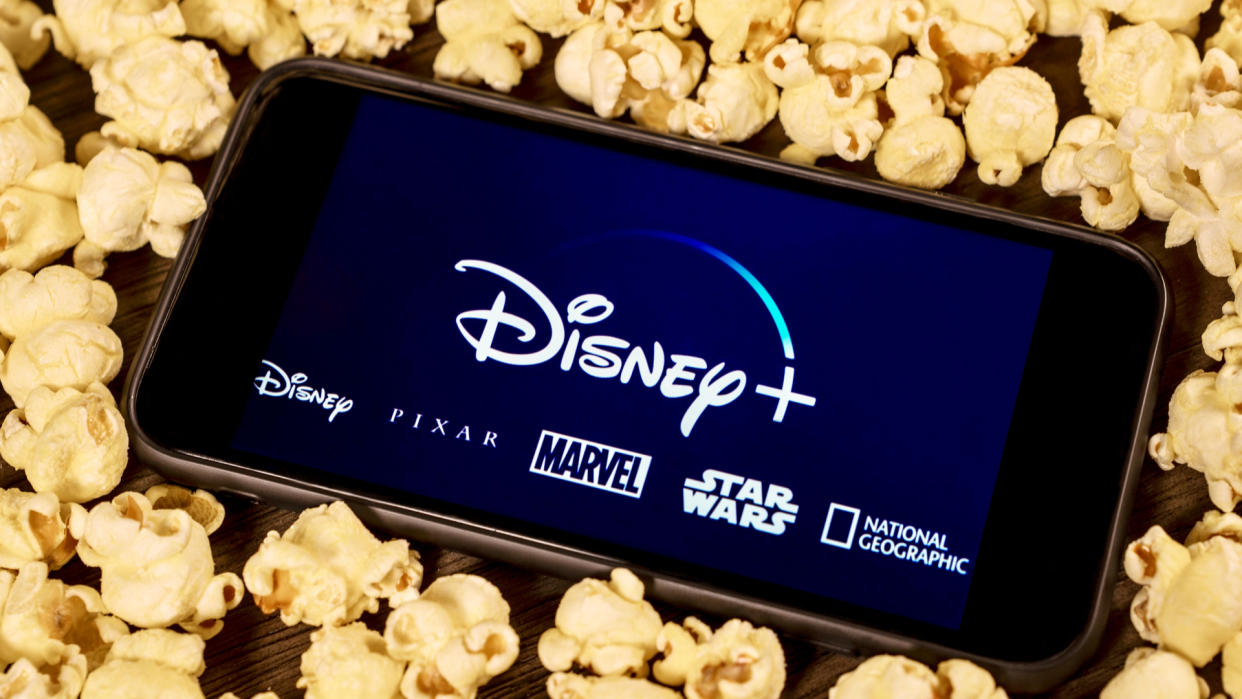  An image of the Disney Plus logo on a smartphone surrounded by popcorn 