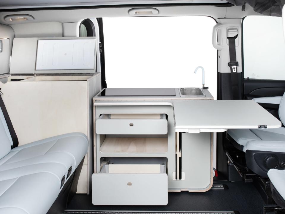Inside the Touring EQV camper van with a kitchen, seats, storage units.