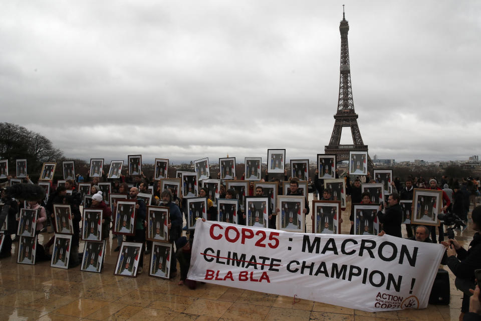 FILE - In this Dec. 8, 2019 file photo, a hundred activists hold portraits of President Emmanuel Macron to urge France to take action during the U.N. COP 25 climate talks in Madrid, during a gathering at Place du Trocadero facing the Eiffel Tower in Paris, France. World leaders breathed an audible sigh of relief that the United States under President Joe Biden is rejoining the global effort to curb climate change, a cause that his predecessor had shunned. (AP Photo/Francois Mori, File)