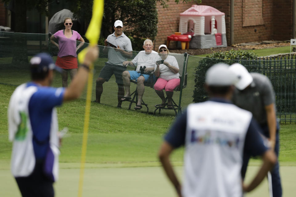 Golf fans watch from a private home near the 17th green during the first round of the World Golf Championship-FedEx St. Jude Invitational Thursday, July 30, 2020, in Memphis, Tenn. (AP Photo/Mark Humphrey)