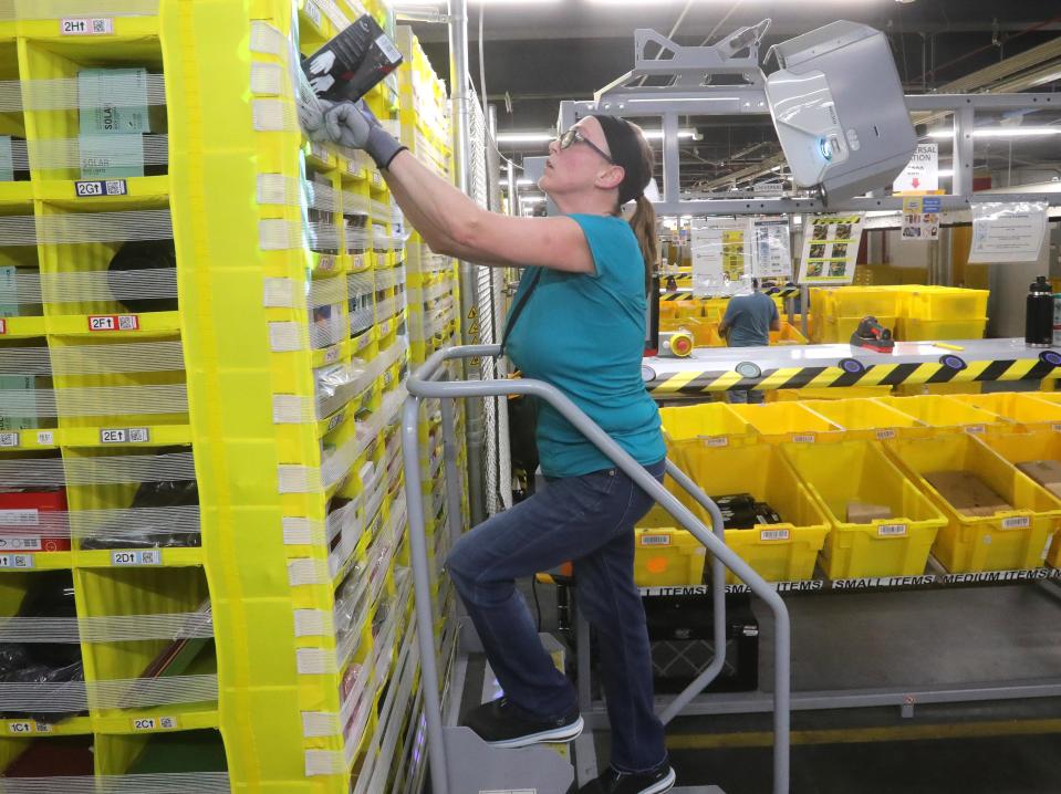 Akron Amazon Fulfillment Center worker Sandra Asbury restocks a pod with merchandise at the facility on Romig Road.