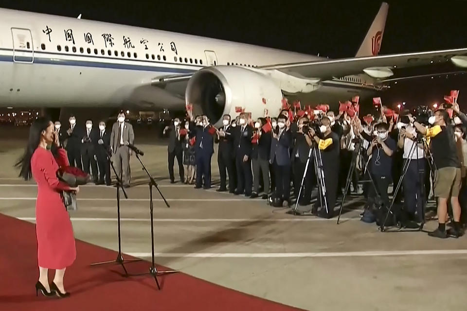 This screen grab made from video released on September 25, 2021 by Chinese state broadcaster CCTV shows people shouting and waving Chinese national flags after Huawei executive Meng Wanzhou (L) arrived following her release, in Shenzhen in China's southern Guangdong province. - - China OUT - XGTY / RESTRICTED TO EDITORIAL USE - MANDATORY CREDIT 