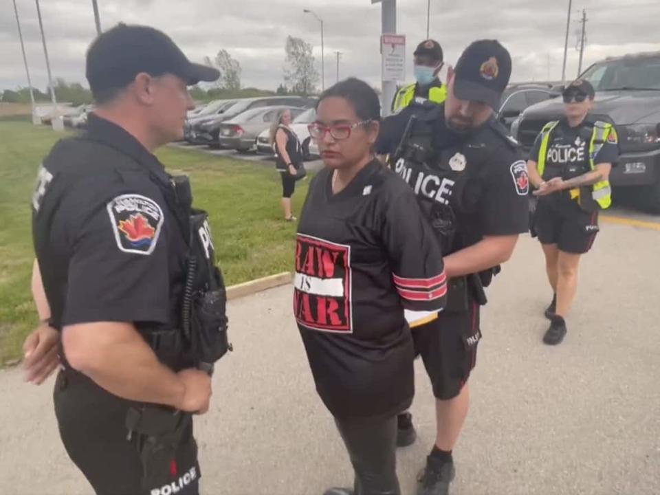 A video shared by Caryma Sa'd appears to show her being arrested outside a rally for Progressive Conservative Leader Doug Ford in Hamilton on Thursday. The Toronto lawyer and political commentator was ticketed for trespassing. (Caryma Sa'd/Twitter - image credit)