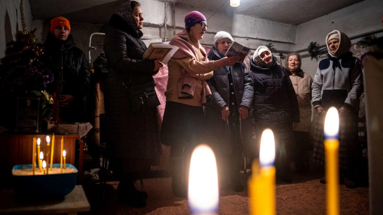 Worshippers pray during an Orthodox Christmas mass in a basement shelter in Chasiv Yar, Eastern Ukraine, on January 7, 2023, amid the Russian invasion of Ukraine. - As artillery boomed outside and fighter jets flew overhead, Orthodox Christians in a battered east Ukraine town held a Christmas service in a basement shelter on January 7, vowing not to let war ruin the holiday. (Photo by Dimitar DILKOFF / AFP)