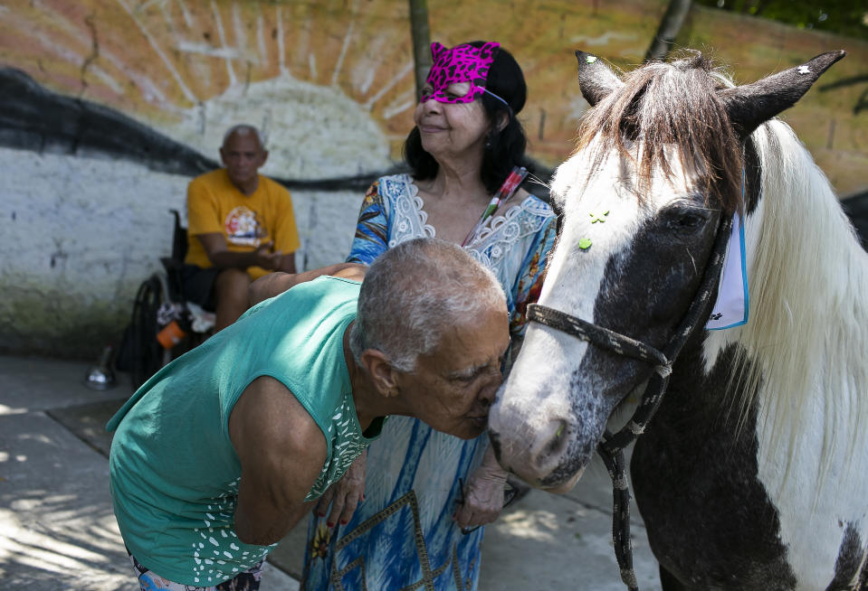 An elderly person kisses a horse named Tony at the "Casa de Repouso Laços de Ouro" nursing home in Sepetiba, Brazil, Thursday, Oct. 1, 2020. The Golias organization brought several animals, who they rescued from abandonment, to provide a little relief from the isolation many elderly people feel, cut off from friends and family due to fear of contagion from the new coronavirus. (AP Photo/Bruna Prado)