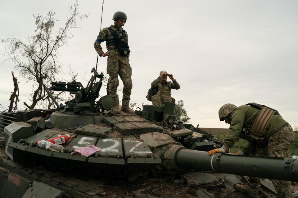 Ukrainian servicemen standing on top of a Russian tank (Copyright 2022 The Associated Press. All rights reserved.)