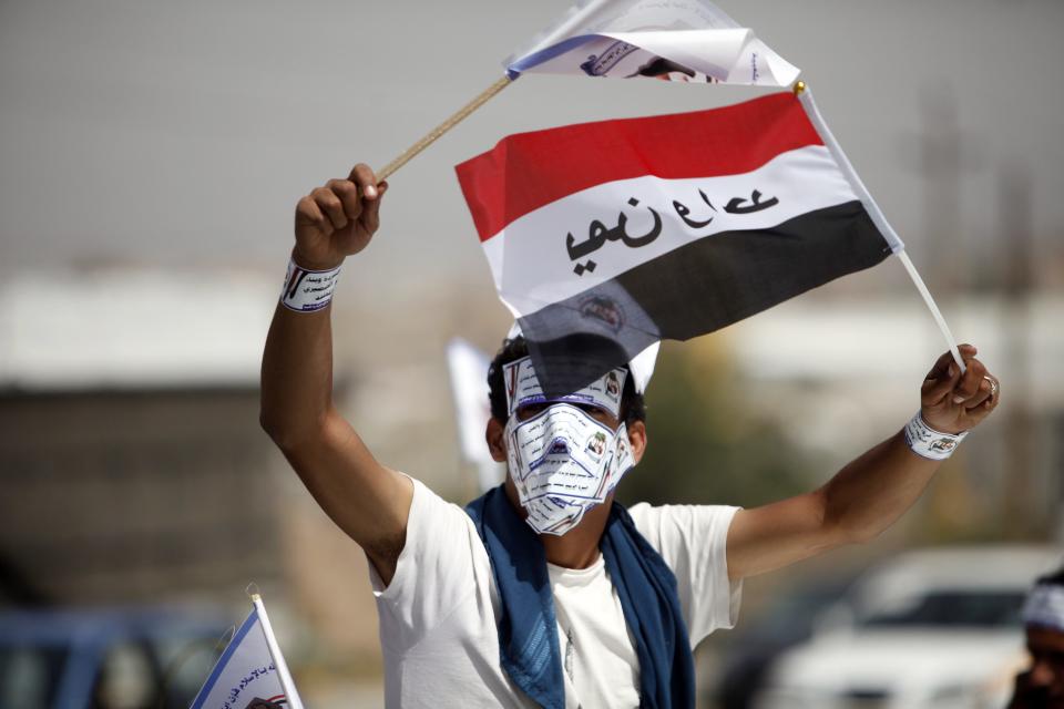 Protester waves flags as he rides atop a vehicle during a protest against proposed constitutional amendments in Sanaa