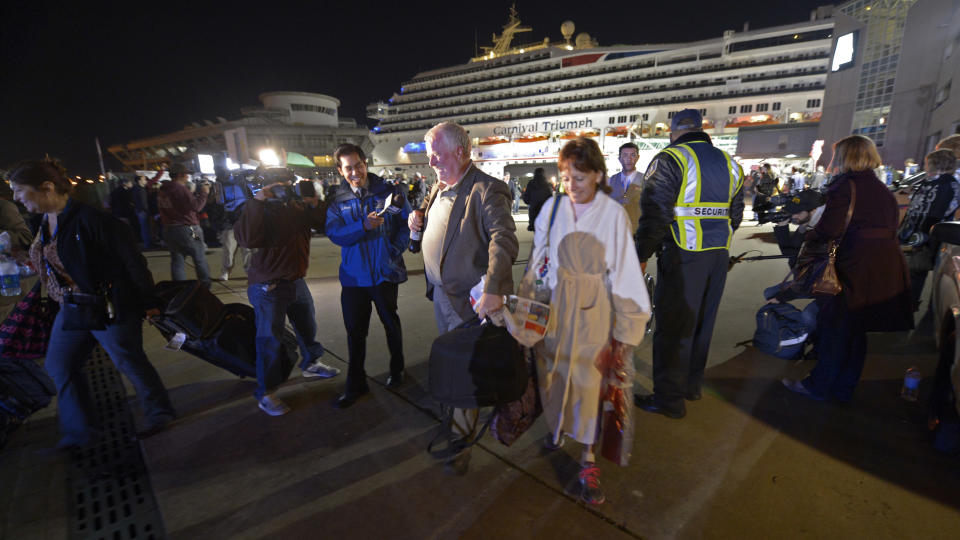 Passengers from the cruise ship Carnival Triumph are questioned by reporters after they disembarked in Mobile, Ala., Thursday, Feb. 14, 2013. The ship with more than 4,200 passengers and crew members has been idled for nearly a week in the Gulf of Mexico following an engine room fire. (AP Photo/John David Mercer)