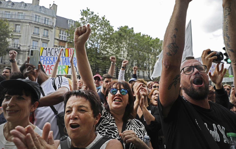 Protestors raise their fists during a demonstration in Paris, France, Saturday, July 31, 2021. Demonstrators gathered in several cities in France on Saturday to protest against the COVID-19 pass, which grants vaccinated individuals greater ease of access to venues. (AP Photo/Adrienne Surprenant)