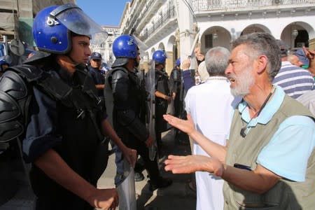 A demonstrator gestures in front of police officers standing guard during a protest against a proposed new hydrocarbons law in Algiers