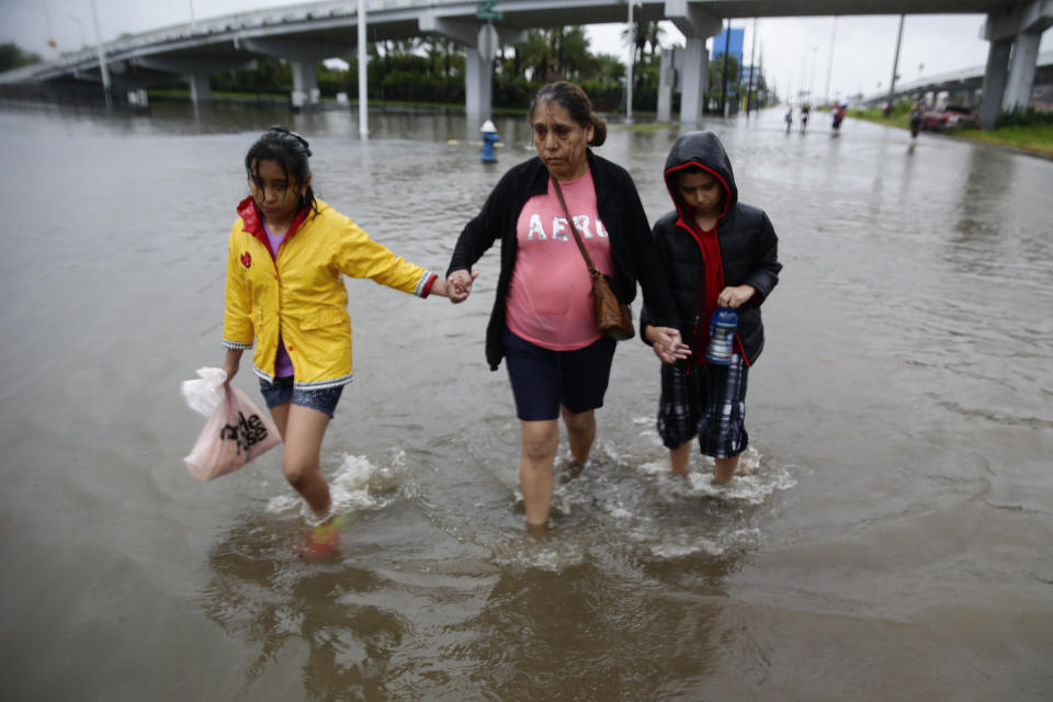 Ofelia Castro leads her grandchildren across a flooded street as they continue an hours long trek from their flooded house in the Edgewood area of South Houston to a relatives apartment miles away.