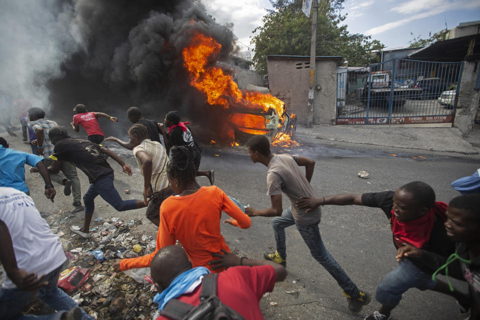 Demonstrators run away from police who were shooting in their direction, as a car burns during a protest demanding the resignation of Haitian President Jovenel Moise in Port-au-Prince, Haiti, Feb. 12, 2019. The image was part of a series of photographs by Associated Press photographers which was named a finalist for the 2020 Pulitzer Prize for Breaking News Photography. (AP Photo/Dieu Nalio Chery)